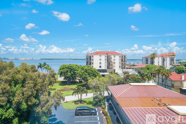 A car is parked in a parking lot in front of a building with a red roof.