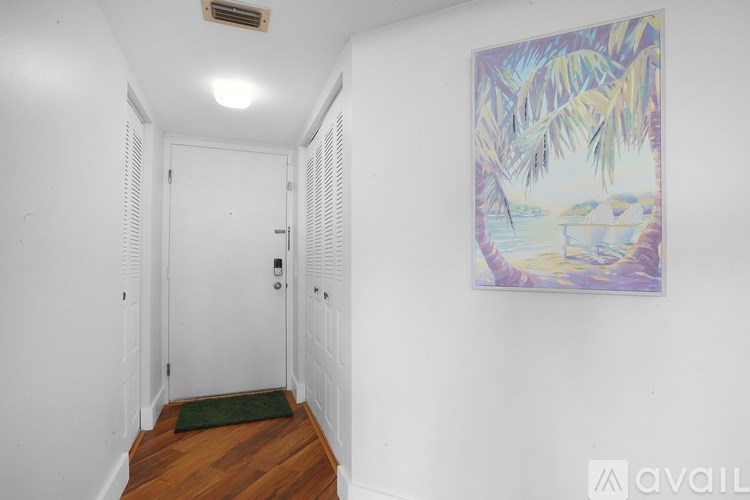 A hallway with a painting on the wall and a green rug on the floor.
