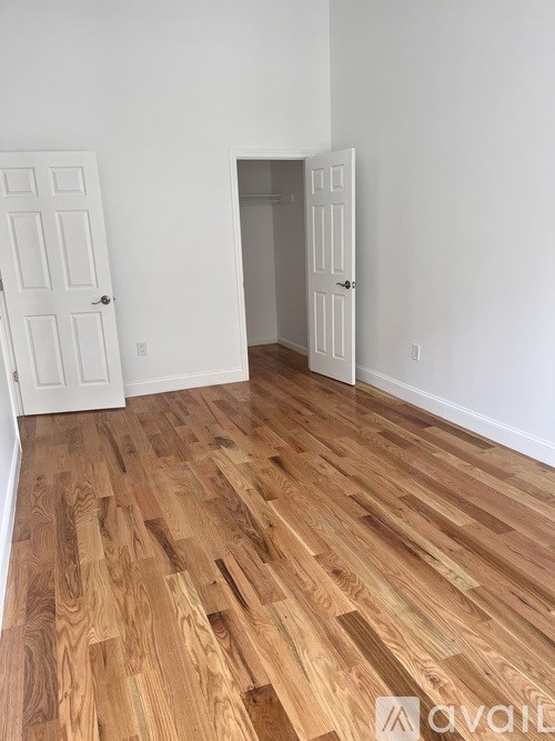 A room with wooden flooring and two white doors.