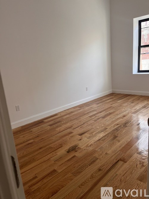 A room with wooden flooring and a window.
