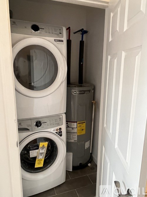 A white washing machine is in a cabinet next to a white door.