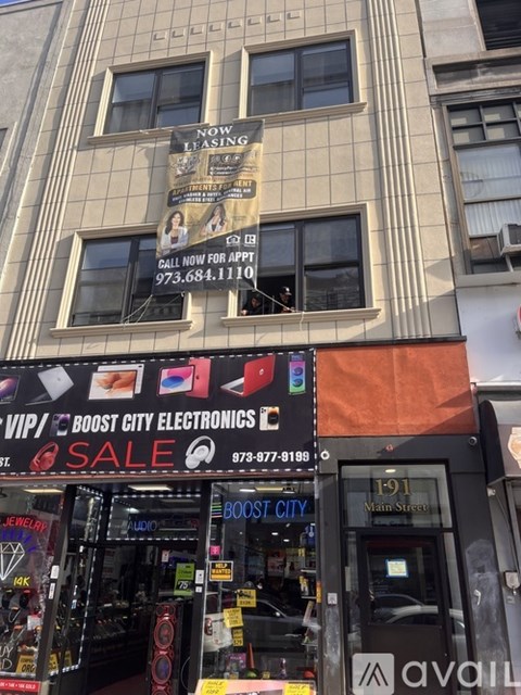 A storefront with a sign that says "Boost City Electronics" and a phone number below it.