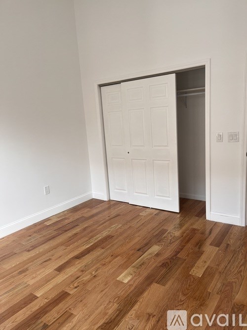 A room with a white door and wooden flooring.