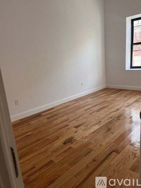 A room with wooden flooring and a window.