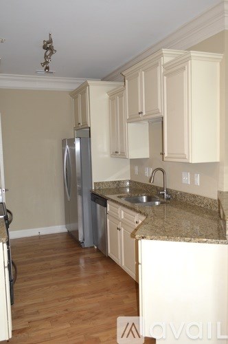 A kitchen with a refrigerator, sink and cabinets.