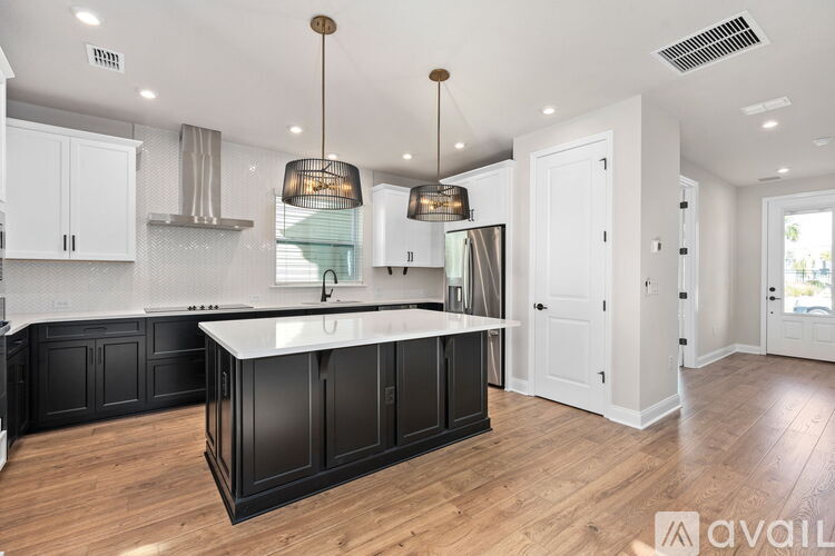 A kitchen with black cabinets and a wooden floor.