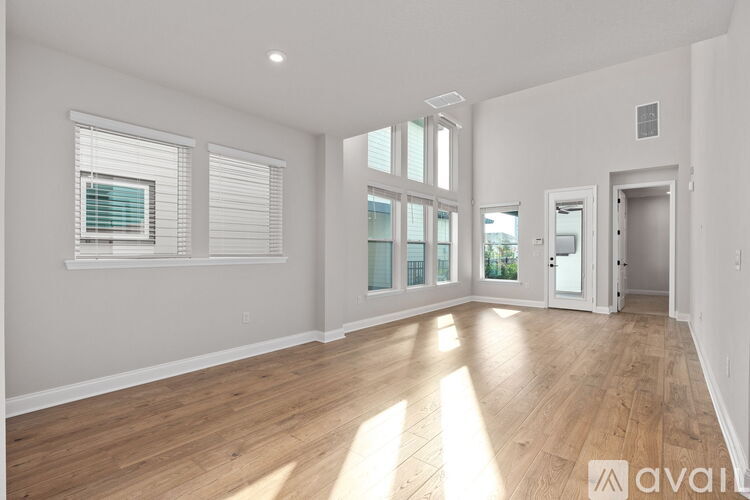 A spacious room with wooden flooring and large windows.