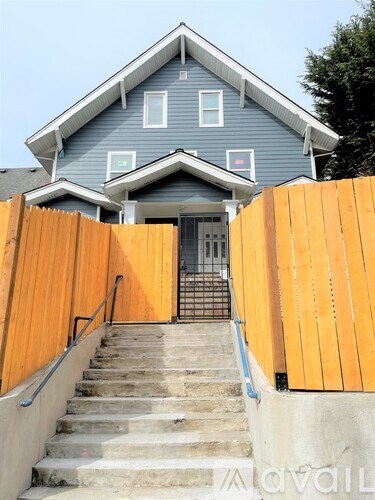 A blue house with a wooden fence and stairs leading to the front door.