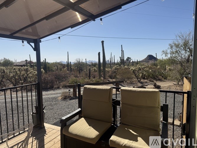 Two chairs are on a balcony overlooking a river and desert landscape.
