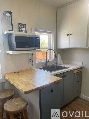 A kitchen with a wooden countertop and a microwave on a shelf.