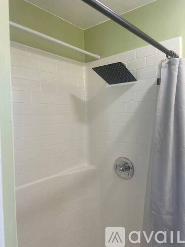 A shower area with a white curtain and a silver shower head.