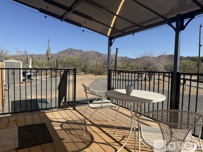 A patio with a table and chairs overlooking a mountainous landscape.