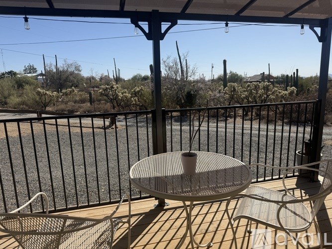 A patio with a table and chairs overlooking a road.