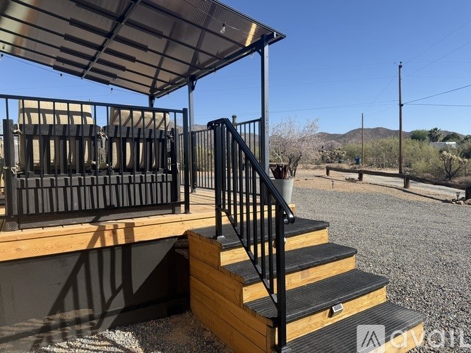 A wooden staircase with a metal railing leads up to a covered patio area.