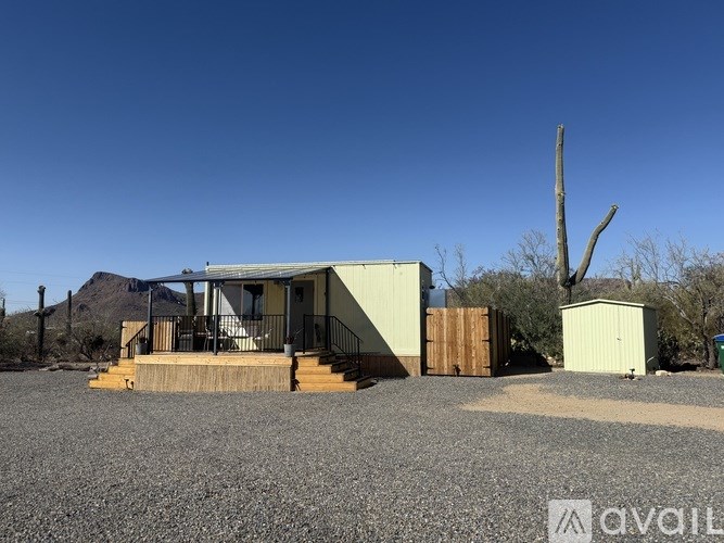 A house with a gravel yard in front and a dead tree in the background.