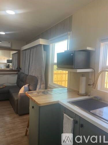 A kitchen area with a grey couch and a television on top of the counter.