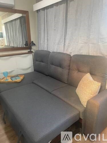A grey sofa with a pillow on it in a room.