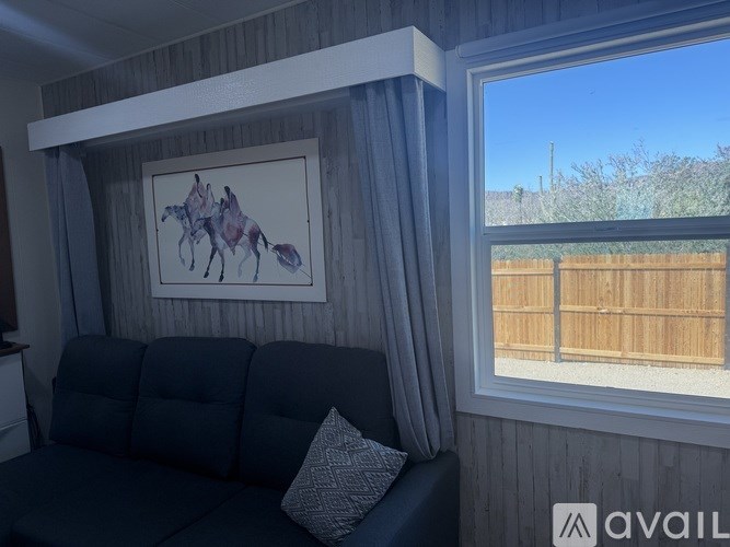 A living room with a grey couch and a painting of a horse on the wall.