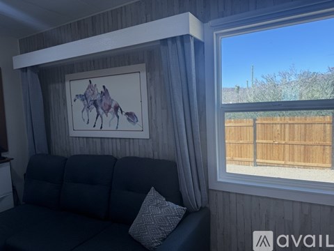 A living room with a grey couch and a painting of a horse on the wall.