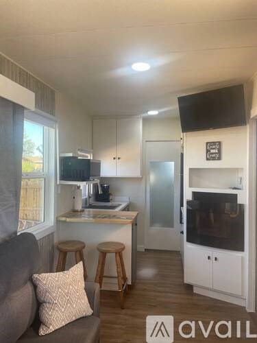 A modern kitchen with a grey couch and wooden stools.
