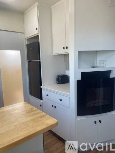 A kitchen with white cabinets and a wooden countertop.