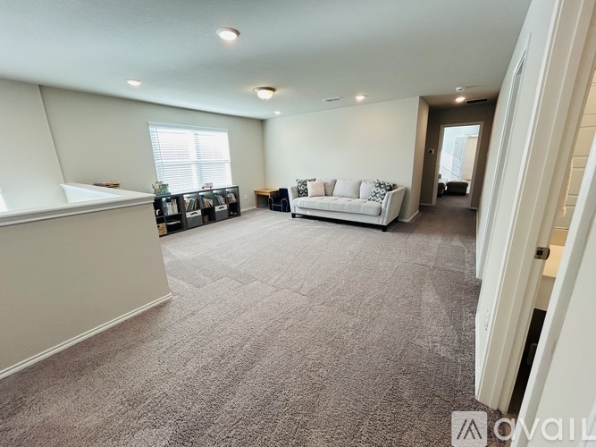 A spacious living room with a white sofa and a grey carpet.