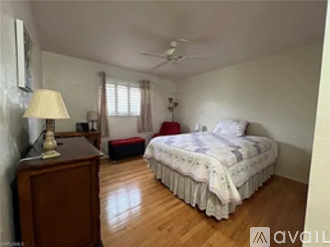 A bedroom with a bed, nightstand, and window.
