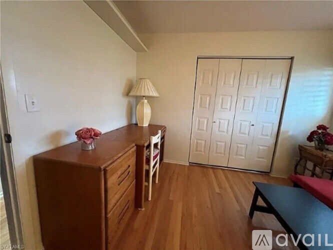 A room with a wooden cabinet, a table with a vase of flowers, and a sliding door.