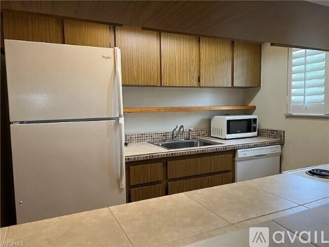 A kitchen with a white refrigerator, wooden cabinets, and a tiled backsplash.
