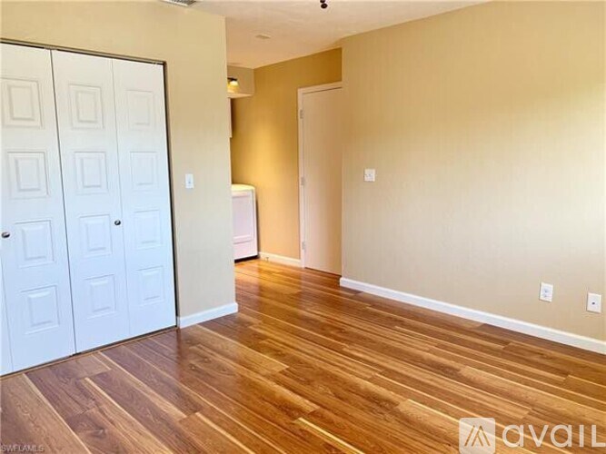 A room with a white door and wooden flooring.