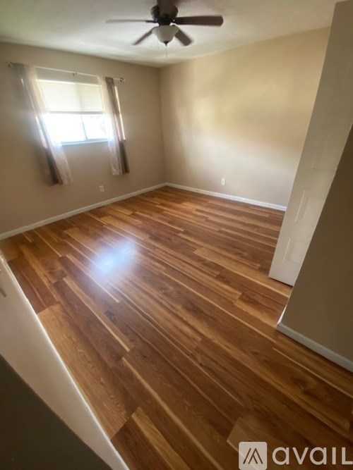 A room with wooden flooring and a ceiling fan.