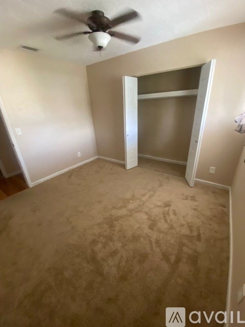 A room with a ceiling fan and a closet with a door open.