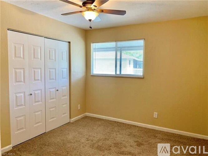 A room with a ceiling fan and a window with blinds.