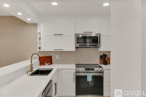 A modern kitchen with a stainless steel oven and white cabinets.