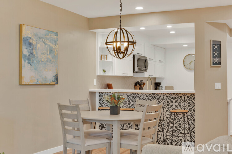 A dining room with a table set for two and a painting on the wall.