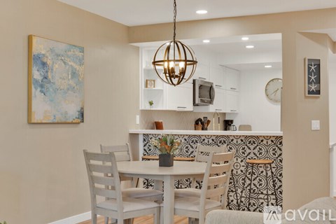 A dining room with a table set for two and a painting on the wall.