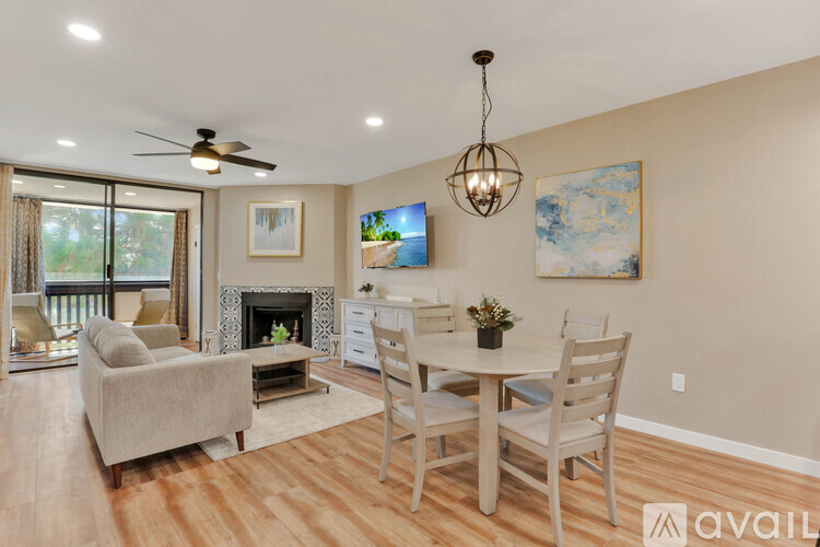 A living room with a fireplace, a couch, a chair, a dining table and a painting on the wall.