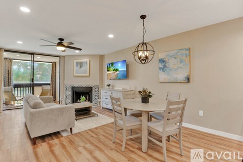 A living room with a fireplace, a couch, a chair, a dining table and a painting on the wall.