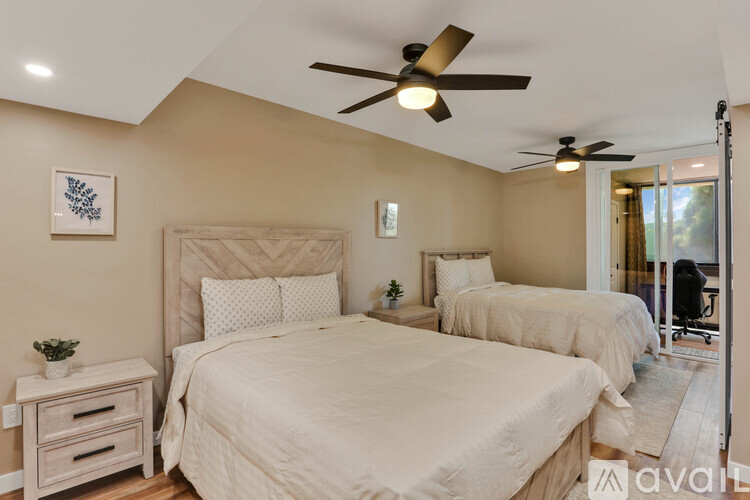 A bedroom with two beds and a ceiling fan.