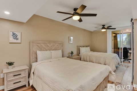 A bedroom with two beds and a ceiling fan.
