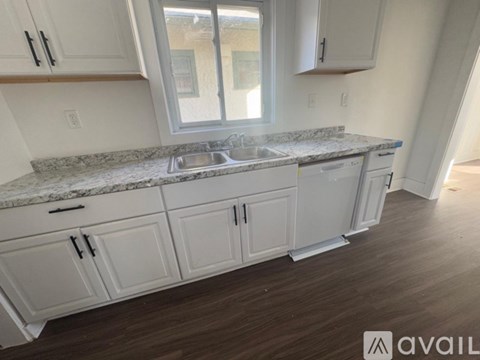 A kitchen with white cabinets and a marble countertop.