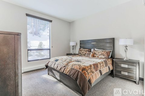A bedroom with a large bed and a window overlooking a snowy landscape.