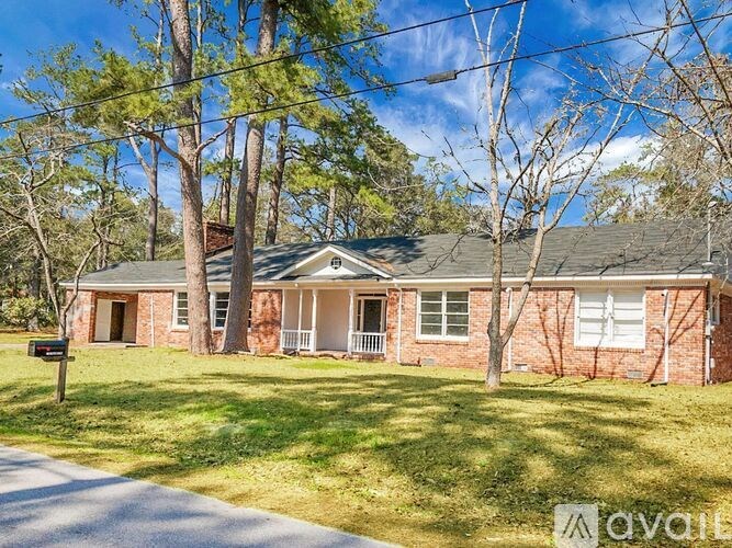 A house with a brick facade and a white door is surrounded by trees.