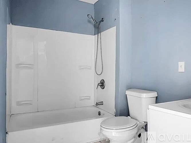 A white toilet sits next to a white bathtub in a bathroom.