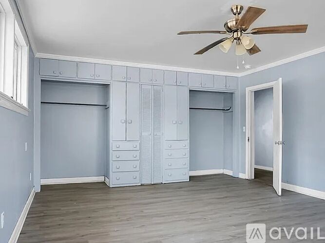 A room with a ceiling fan and a door is shown.