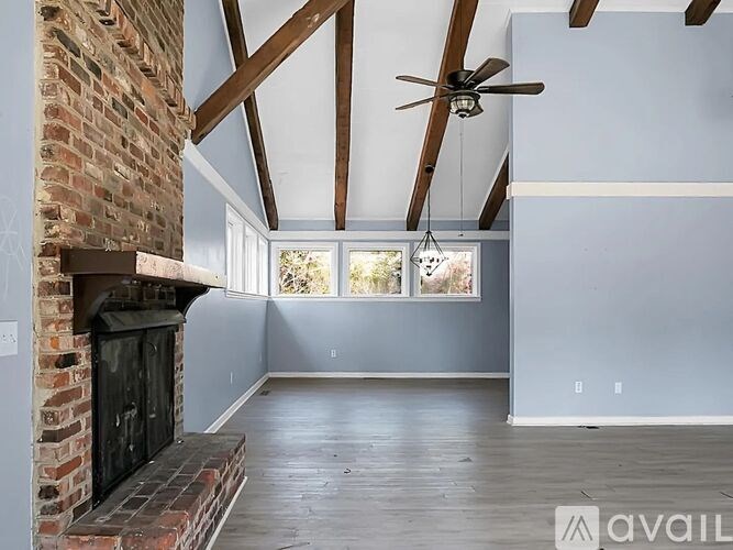 A room with a brick fireplace and a ceiling fan.