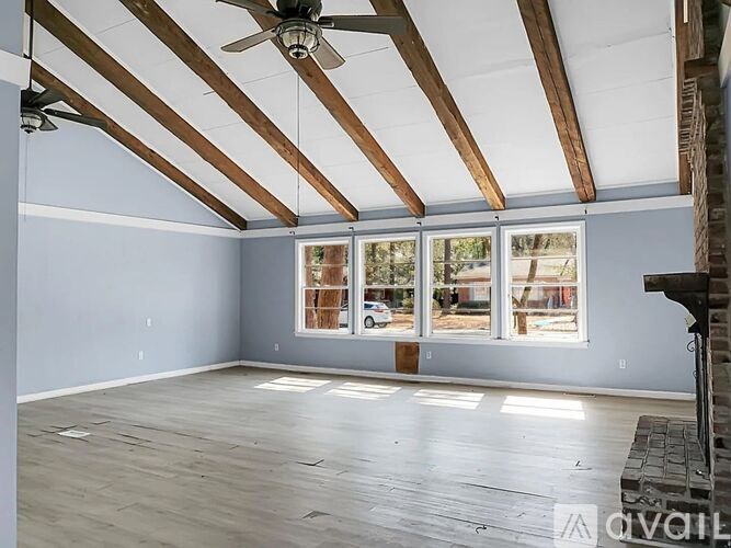 A room with a ceiling fan and large windows.