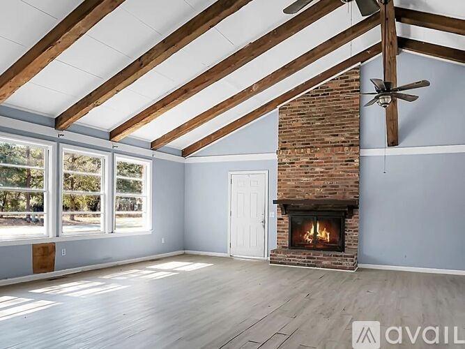 A spacious room with a fireplace and a ceiling fan.