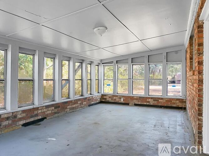 A room with a white ceiling and brick walls with large windows.