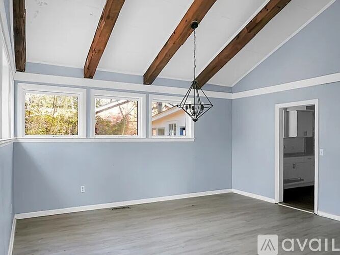 A room with a hanging chandelier and a door leading to another room.